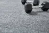 Two black dumbbells are placed on a gray carpeted surface. Produktbild-Vorschau