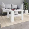 A white coffee table is placed on a rug in front of a grey couch, with a plant in a white pot in the background. Náhled obrázku produktu