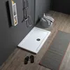 A modern bathroom scene featuring a rectangular acrylic shower tray, a shower fixture, a shelf with toiletries, a stool with a towel and soap, flip-flops, and a bath mat. Anteprima dell’immagine prodotto