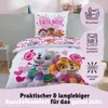 A Paw Patrol themed bedding set is displayed on a bed, with close-ups of the characters and icons indicating washing and drying instructions. Produktbild-Vorschau