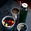 A breakfast setting with a glass water bottle, a mug of coffee, and two bowls of fruit and nuts. Anteprima dell’immagine prodotto