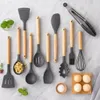 A collection of grey silicone kitchen utensils with wooden handles arranged on a light grey marble-like surface. Náhľad obrázku produktu