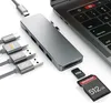 A USB-C hub adapter is shown connected to a laptop, with various cables and memory cards nearby. Produktbild-Vorschau