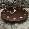 A wooden wall clock with beige numbers and hands is displayed on a textured gray background. Produktbild-Vorschau