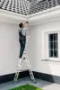 A man is on a ladder installing a security camera on the exterior wall of a house. Podgląd zdjęcia produktu