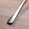 A close-up shot of a silver spoon on a wooden surface. Produktbild-Vorschau