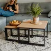 A woman is sitting on a sofa next to nesting coffee tables with a plant and a book on them. Anteprima dell’immagine prodotto