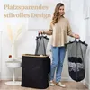 A woman is holding two laundry bags next to a large black laundry basket. Produktbild-Vorschau
