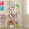 A multi-sport equipment stand filled with various sports balls, rackets, and other equipment, placed indoors against a wall. Anteprima dell’immagine prodotto