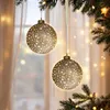Two illuminated Christmas ornaments hang from a pine branch in front of a window with soft curtains and bokeh lights. Náhled obrázku produktu