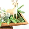 A decorative deer figurine surrounded by pine branches in a wooden planter. Produktbild-Vorschau