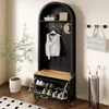 A hallway or entryway with a black arched hall tree featuring a bench, shoe storage, hooks, and a shelf. A plant and a rug are also visible. Produktbild-Vorschau