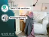 A living room scene with a sofa and blankets, featuring product certifications and care instructions. Produktbild-Vorschau
