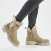 A person wearing grey jeans and beige winter boots. Voir les images du produit