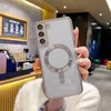 A person is holding a clear phone case with a silver magnetic ring on the back, in what appears to be a cafe or restaurant setting. Anteprima dell’immagine prodotto