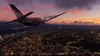 A small airplane flies over a city at dusk. Produktbild-Vorschau
