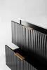 A close-up view of two drawers of a black cabinet with fluted fronts and gold handles, against a white background. Anteprima dell’immagine prodotto