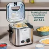 A mini deep fryer with its lid open, showing fries inside, placed on a countertop with bowls of ketchup and dipping sauce nearby. Produktbild-Vorschau