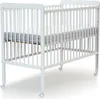 A white wooden baby crib with a mattress inside, shown from a slightly elevated front-side angle on a white background. Anteprima dell’immagine prodotto