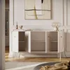 A white sideboard with its doors open, displaying shelves, in a well-lit room with a painting on the wall and a lamp on top. Produktbild-Vorschau