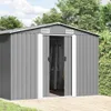 A grey metal garden shed with its doors open, showing a ladder inside. It is set in an outdoor environment with trees and a paved patio. Náhled obrázku produktu
