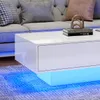 A modern living room scene featuring a white high-gloss coffee table with LED lighting, placed on a rug in front of a gray sofa. Produktbild-Vorschau