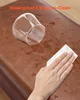 A hand is wiping water off a brown leather ottoman with a white cloth, next to a clear glass. Podgląd zdjęcia produktu