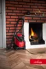 A red and black LEHMANN Haddo industrial vacuum cleaner is positioned next to a fireplace with a fire burning. The scene is set in a room with a brick wall and wooden floor. Náhľad obrázku produktu