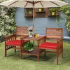 A wooden garden bench set with a table and umbrella on a grassy lawn, with a brick wall and plants in the background. Náhled obrázku produktu