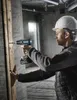 A construction worker is using a drill to make a hole in a wooden plank. Produktbild-Vorschau