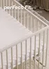 A close-up view of a crib with a patterned sheet. Produktbild-Vorschau