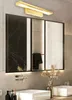 A modern bathroom vanity with a large mirror and a gold wall lamp above it. Produktbild-Vorschau