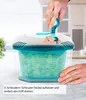 A person's hands are shown operating a salad spinner in a kitchen setting. Produktbild-Vorschau