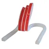 A close-up shot of a white silicone shower threshold with red and white adhesive tape. Voir les images du produit