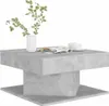 A square coffee table with a concrete-like finish, shown against a white background. A white vase with green foliage and two white teacups on saucers are placed on top of the table. Náhled obrázku produktu
