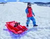 A child in winter clothing pulls a red sled through the snow on a sunny day. Produktbild-Vorschau