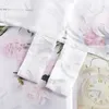 A close-up of white curtains with a floral pattern, layered over an image of pink peonies and a vintage alarm clock. Produktbild-Vorschau