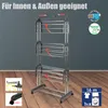 A multi-level drying rack with wheels, shown indoors against a gray wall and on a wooden floor. There are inset images showing how to use the product. Produktbild-Vorschau