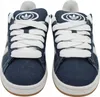 A front-on view of a pair of blue denim Adidas sneakers with white laces and white Adidas logos on the tongue. Náhled obrázku produktu