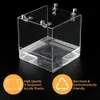 A clear acrylic bird bath with metal hooks attached to the top, set against a black background. Two circular orange overlays with text and icons are present at the bottom. Produktbild-Vorschau