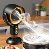A black and gold fan is shown on a wooden countertop, blowing smoke away from a pot of food. Produktbild-Vorschau