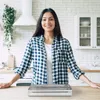 A woman stands in a kitchen next to a vacuum sealer. Produktbild-Vorschau