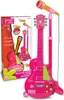 A pink electronic guitar with a stand and microphone, presented in its packaging. Voir les images du produit