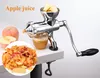 A manual apple juicer is shown on a white surface, with apples and apple pulp in the foreground. Produktbild-Vorschau