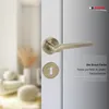 A close-up of a bronze door handle and keyhole on a white door, with a blurred background of a room interior. Produktbild-Vorschau