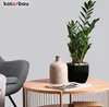 A plant pot and vase on a coffee table next to a chair. Náhľad obrázku produktu