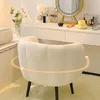 A white fluffy chair in front of a white vanity table with makeup and accessories. Produktbild-Vorschau