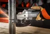 A hand wearing a glove is using an angle grinder to cut a metal pipe, with sparks flying. Náhľad obrázku produktu
