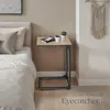 A bedside table next to a bed with a book and a mug on it. Produktbild-Vorschau