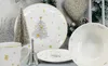 A Christmas-themed dinnerware set is displayed on a table with festive decorations. Produktbild-Vorschau